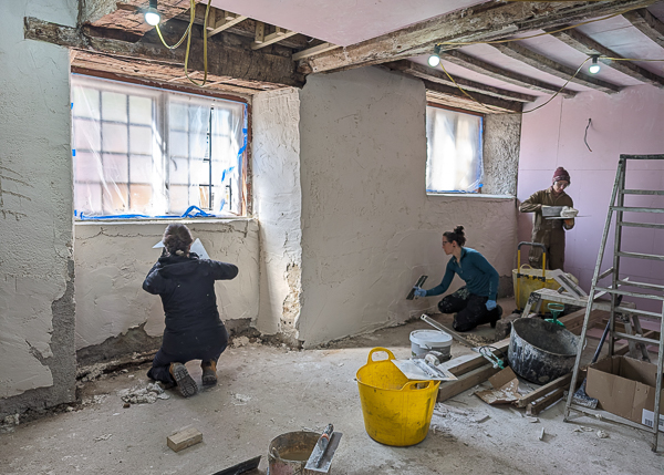 A group of people plastering inside an old building 